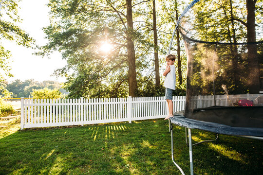 Boy Standing on side of trampoline during sunset