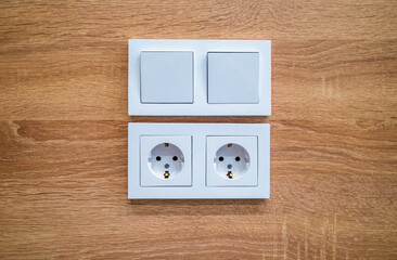 House electrics, white light switches and electrical plugs fitted into wooden paneling. Energy connections.