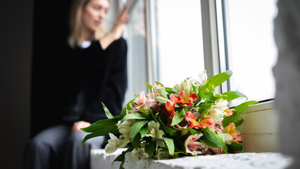 Elegant, emotional girl in a black jacket sits in the background with a beautiful spring bouquet of...