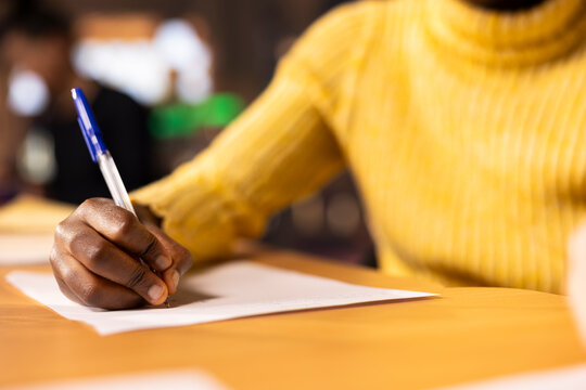 African american teen solving the school assignment for literature class lesson, writing descriptive or narrative ideas for a new essay. Girl preparing with research done for the course. Close up.