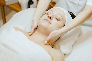 A girl cosmetologist massages the neck of a patient.