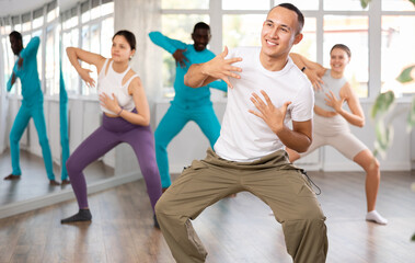 Young guy and international dancers preparing their modern dance performance at light dance studio