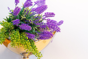 Lavender flowers bouquet composition in a golden vase against white background, spring home decor.