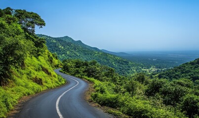 Fototapeta premium Winding road through lush green hills under clear blue sky