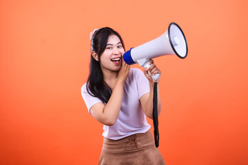 Woman holding a megaphone isolated on an orange background promoting something
