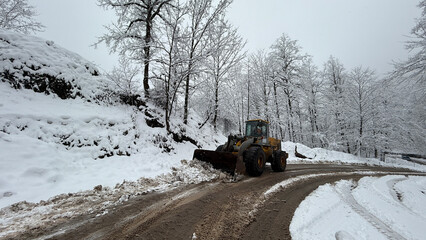 A rugged snowplow works through icy terrain, ensuring safe passage through this serene winter landscape.
