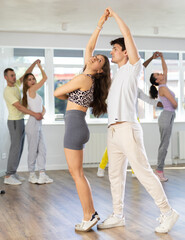 Obraz premium Group of multiethnic active sports girl and guy dancing social dance movements in modern studio