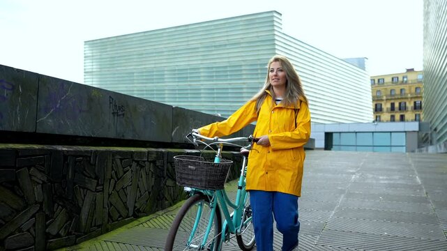 Young woman walking with bicycle in urban setting