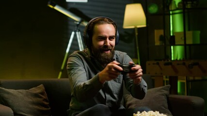 Cheerful gamer celebrating, showing positive emotions after defeating all enemies while playing on gaming console. Man congratulating himself after winning videogame, feeling relieved, camera A