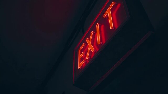 Bright red exit sign illuminates dark hallway in a public building