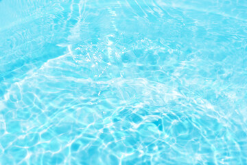 Blue water with ripples on the surface. Defocus blurred transparent blue colored clear calm water surface texture with splashes and bubbles. Water waves with shining pattern texture background.