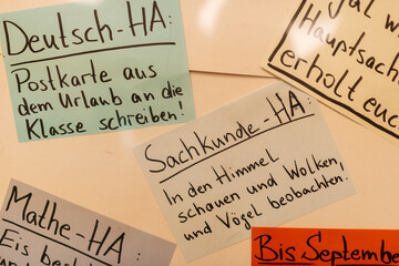 A board with handwritten holiday homework assignments for different school subjects.
