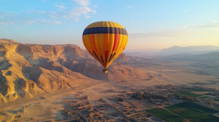 Obraz premium A colorful hot air balloon floats above a desert landscape at dawn