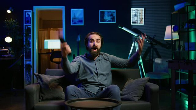 Upset supporter watching sports match, annoyed by team performance, shutting off TV in frustration. Frowning man looking at football competition, appalled by referee decision, camera B