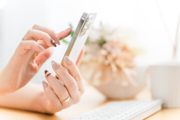 スマホ・スマートフォンの画面をタッチするネイルをした女性
