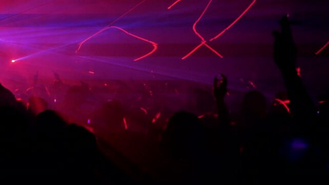 gente bailando con las manos arriba durante un show con laser
