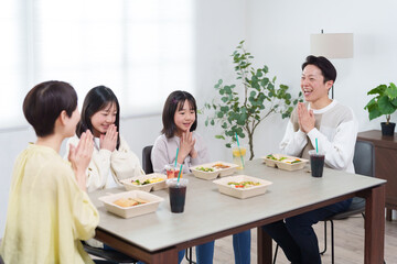 家でデリバリーの弁当を食べる家族