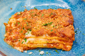 Traditional italian dish lasagna alla bolognese in the blue plate with white background