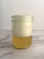 Glass of kombucha in a mason jar glass, large amount of foam