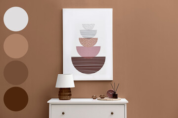 Console table with lamp, candles, clock and reed diffuser near wall in mocha mousse shade. Interior...
