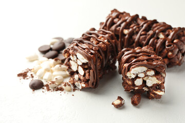 Delicious chocolate puffed rice bars and cacao chips on white table, closeup
