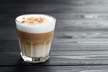 Tasty latte macchiato in glass on black wooden table, closeup. Space for text