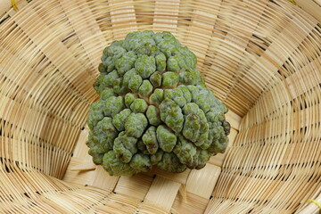 Fresh and organic custard apple on the wooden basket. Famous tropical fruit in Asia. 