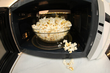 Bowl of tasty popcorn in microwave oven on white marble table, closeup. Fisheye lens effect