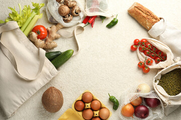 Eco bags with different food products on white textured table, flat lay. Space for text