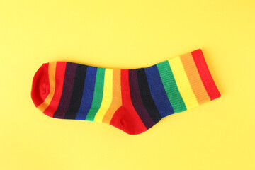One sock in LGBT colors on yellow background, top view
