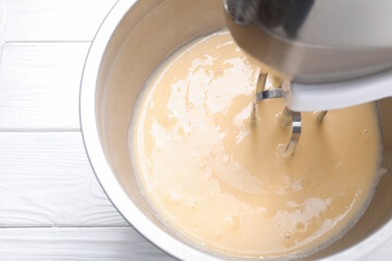 Making dough in bowl of stand mixer at white wooden table, above view