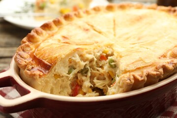 Tasty homemade pie with chicken and vegetables in baking dish on table, closeup