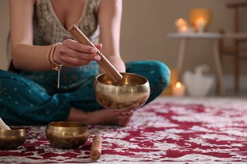 Woman with singing bowls and burning candles indoors, closeup