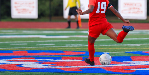 Soccer Player in Red Uniform Takes a Shot at the Soccer Ball on a Vibrant Field