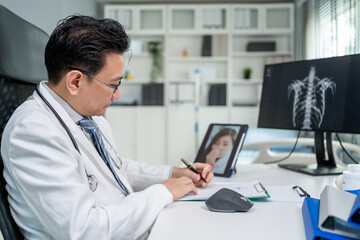 Fototapeta premium Asian doctor providing telehealth video consultation to online patient. 