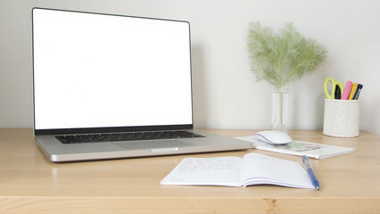 Minimalist workspace featuring a blank laptop screen, modern desk setup with potted plant and organized stationery, ideal for productivity.