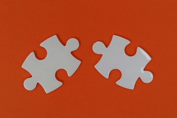 Obraz premium Two white puzzles on an orange background