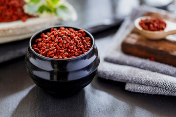 annatto grains in a container on a gray slate