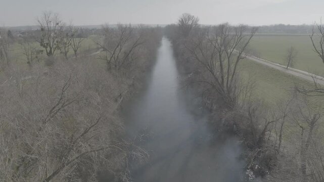 Canal calme survol&eacute; par drone en hiver &ndash; arbres nus et campagne sym&eacute;trique