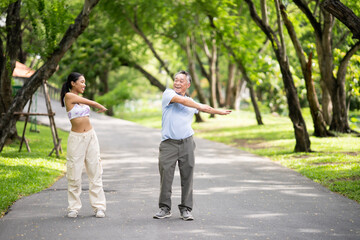 Obraz premium Happy oldery Asian man enjoy exercise with fresh air and nature with daughter. Senior man and a girl workout at park. Healthy retirement and life insurance concept.