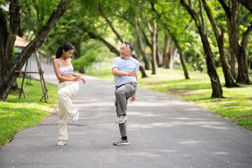 Happy oldery Asian man enjoy exercise with fresh air and nature with his daughter. Senior man and a...