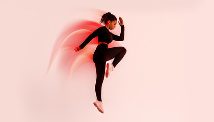 Dynamic moves. Determined African American lady exercising, doing elbow to knee crunches or jumping on red neon studio background, full length, side view