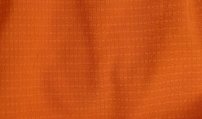Sport Clothing Fabric Texture Background. Top View of Cloth Textile Surface. Orange Football Shirt. Text Space