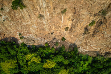 An aerial view of the cliff at Khao E-Bid in Phetchaburi Province, Thailand, shows it glowing orange as it is illuminated by the setting sun.