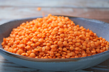 Vibrant orange lentils displayed in a shallow bowl on wooden table