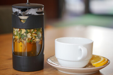 Fresh herbal tea brewing beside a white cup on a wooden table