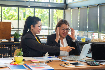 Two business women sit at desk discuss project details, diverse female colleagues met in office, share opinion, working on collaborative task