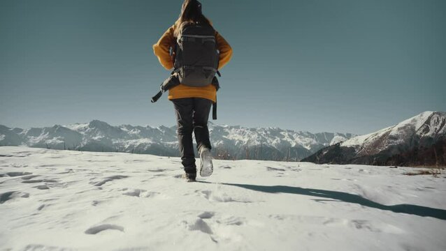 Woman is hiking in snowy winter mountains of Svaneti region in Georgia. View from the back