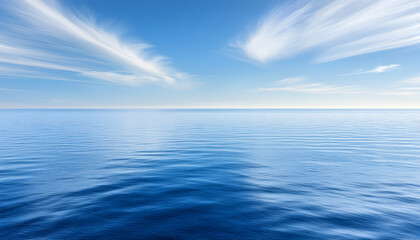 Obraz premium Serene seascape photo featuring a calm ocean under a vibrant blue sky with wispy clouds. Ideal for travel, relaxation, and nature themes.