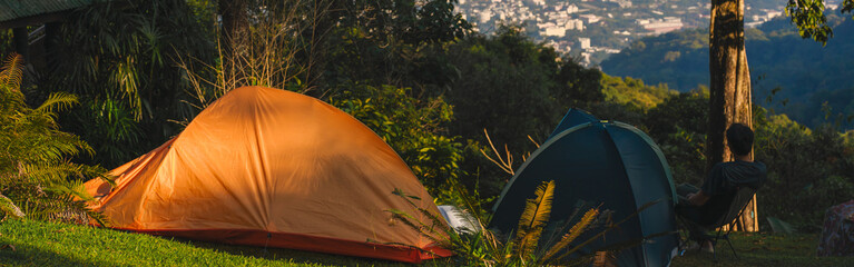 landscape and travel concept with man relax with camping tent on mountain and city background